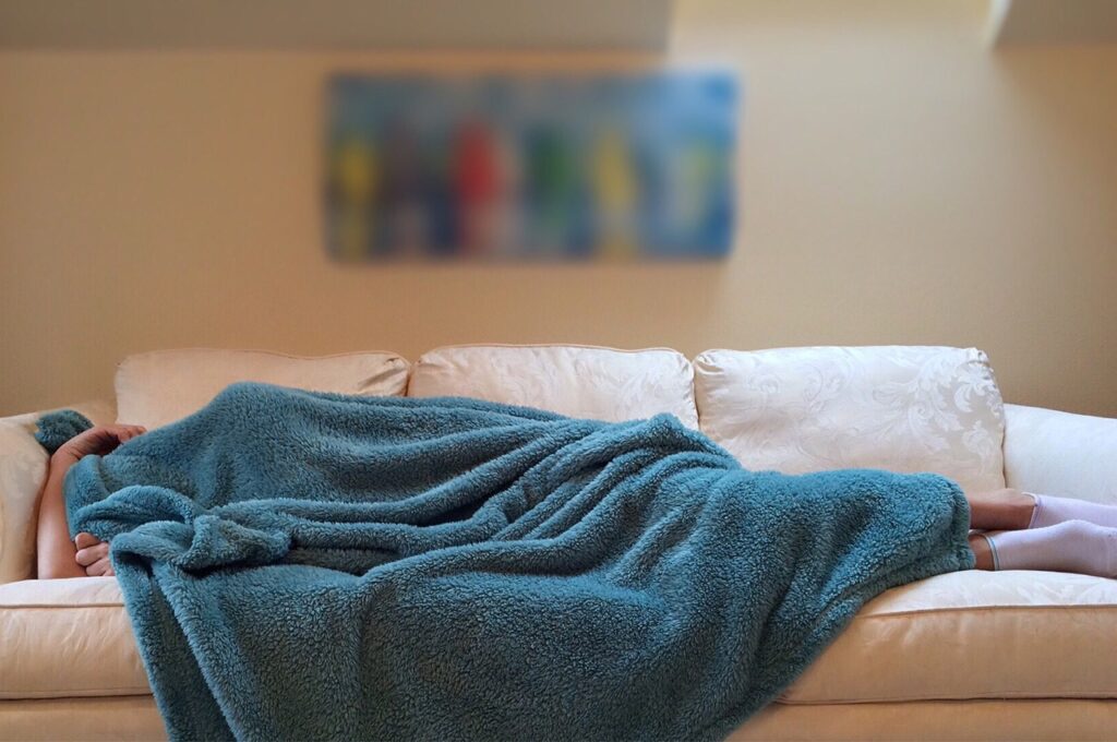 une personne dormant sur un canapé pour renforcer le système immunitaire, bienfaits du sommeil du la santé