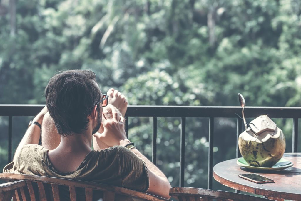 Un homme assis sur un balcon avec une tasse de café.