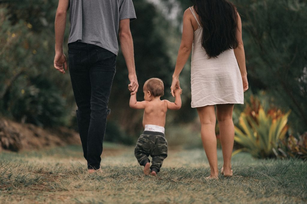 Un homme et une femme se tenant la main avec un bébé marchant sur un chemin.