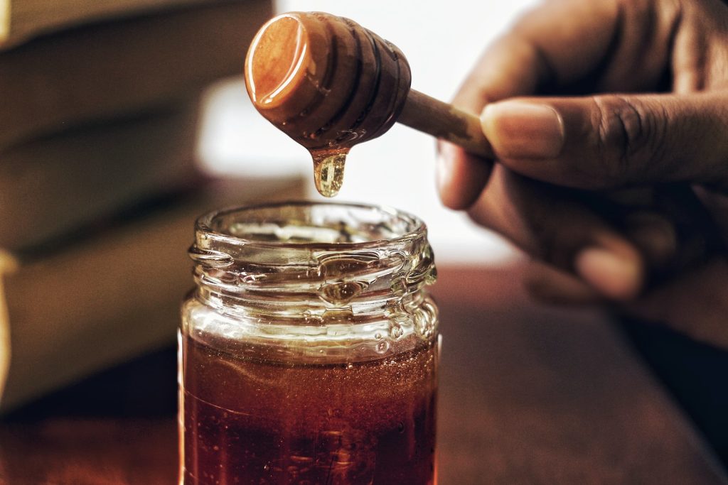 Une personne verse du miel dans un pot.